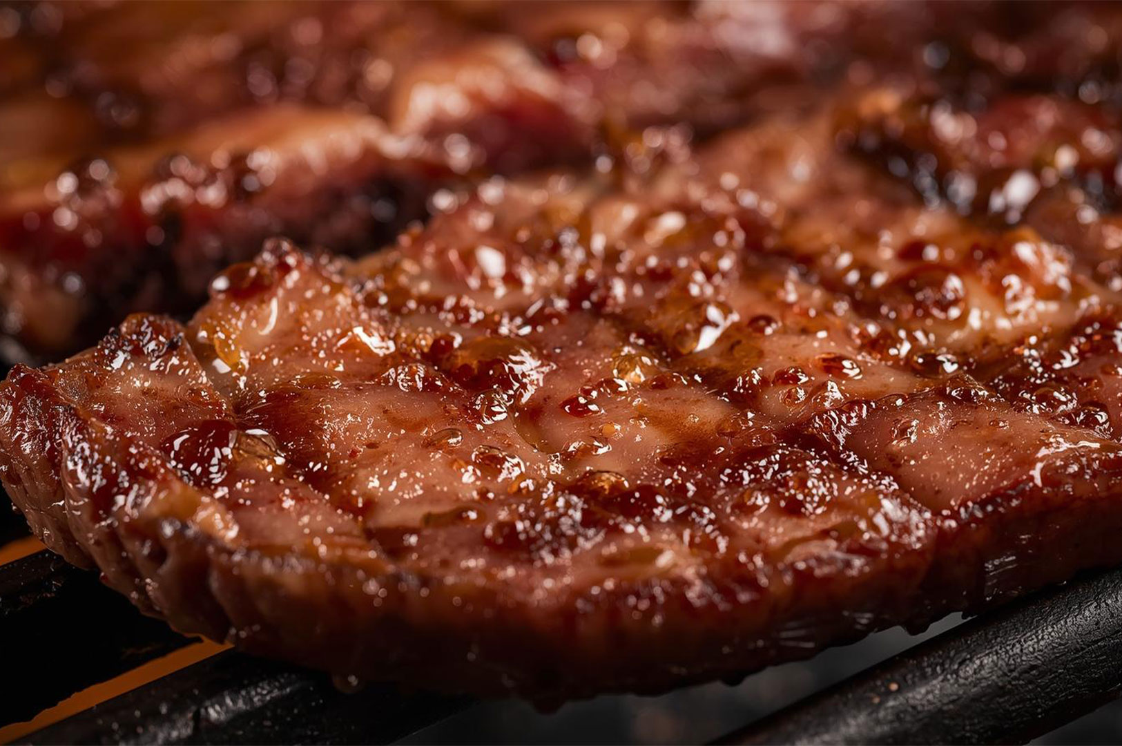 Macro shot of a perfectly cooked, juicy beef steak on a grill, glistening with fat and savory glaze.