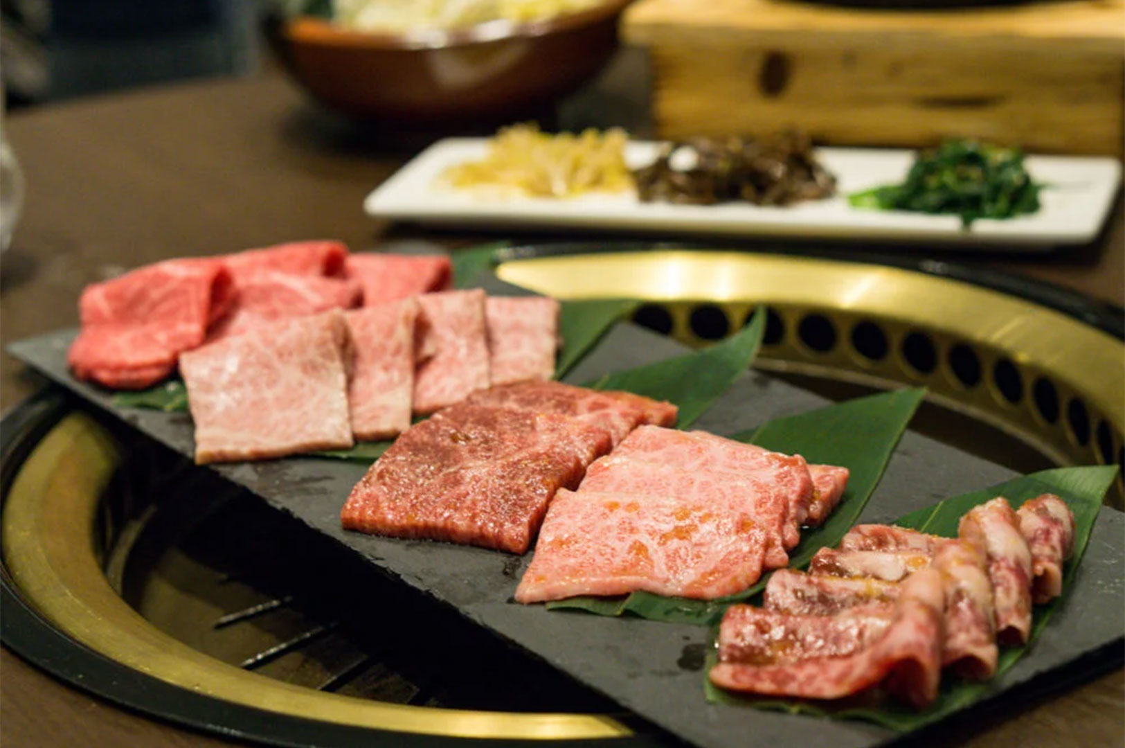 A rectangular slate serving board featuring an assortment of various raw Wagyu beef cuts and textures at a BBQ restaurant.
