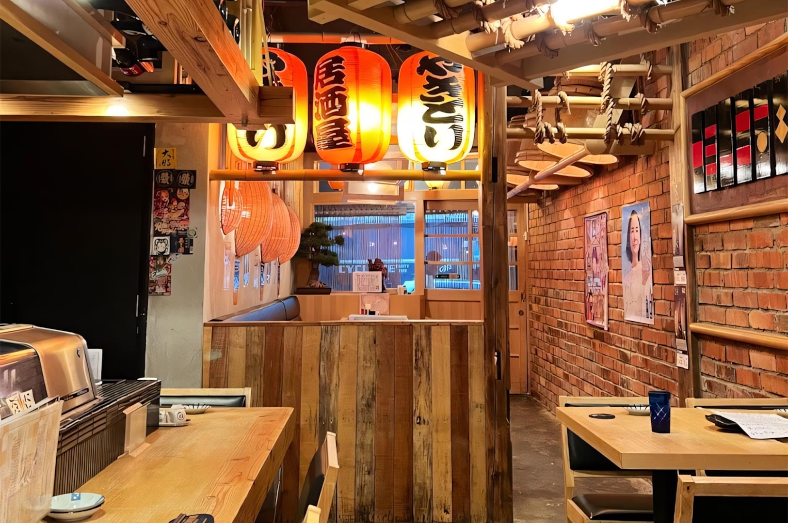 Cozy dining area of a Japanese Izakaya featuring hanging red paper lanterns, exposed brick walls, and warm wooden tables.