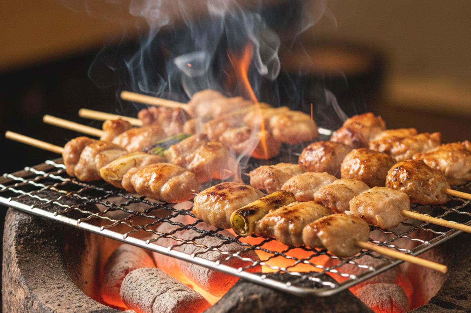 Close-up of various chicken yakitori skewers grilling over glowing charcoal with rising smoke.
