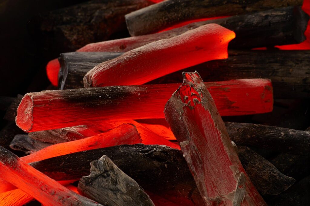 Extreme close-up of glowing red hot binchotan charcoal sticks used for traditional Japanese grilling.