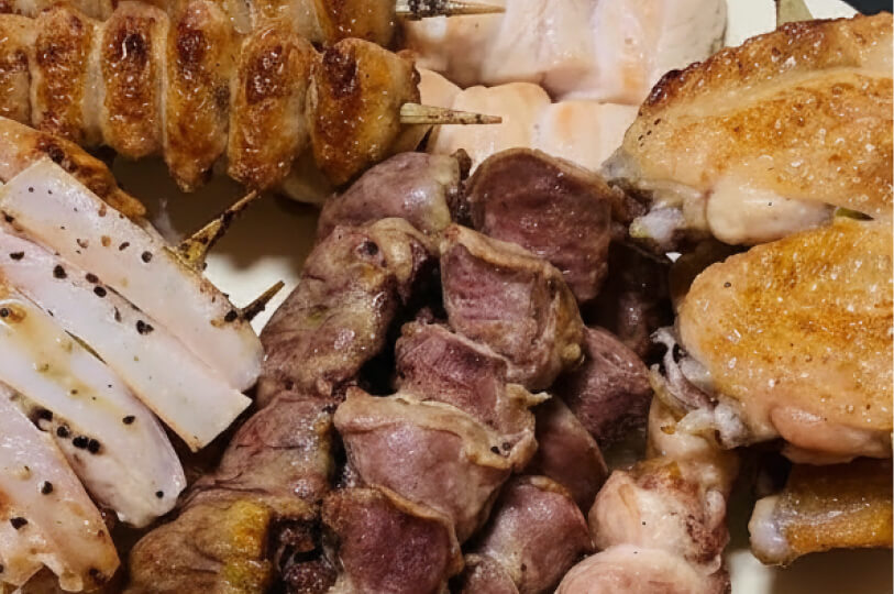 A top-down close-up of a variety of cooked yakitori skewers, including chicken wings and gizzards, seasoned and ready to serve.