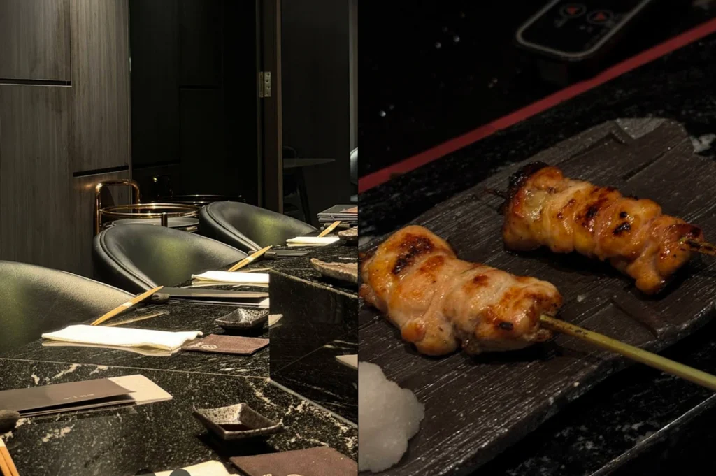 A split-composition image. The left side shows a minimalist, upscale dining area with a polished black marble counter, sleek black leather chairs, and neatly folded white linens. The right side is a close-up of two perfectly grilled, plump chicken skewers served on a textured dark stone plate, accompanied by a small mound of grated daikon radish. The lighting is moody and focused, highlighting the oily sheen of the grilled skin.